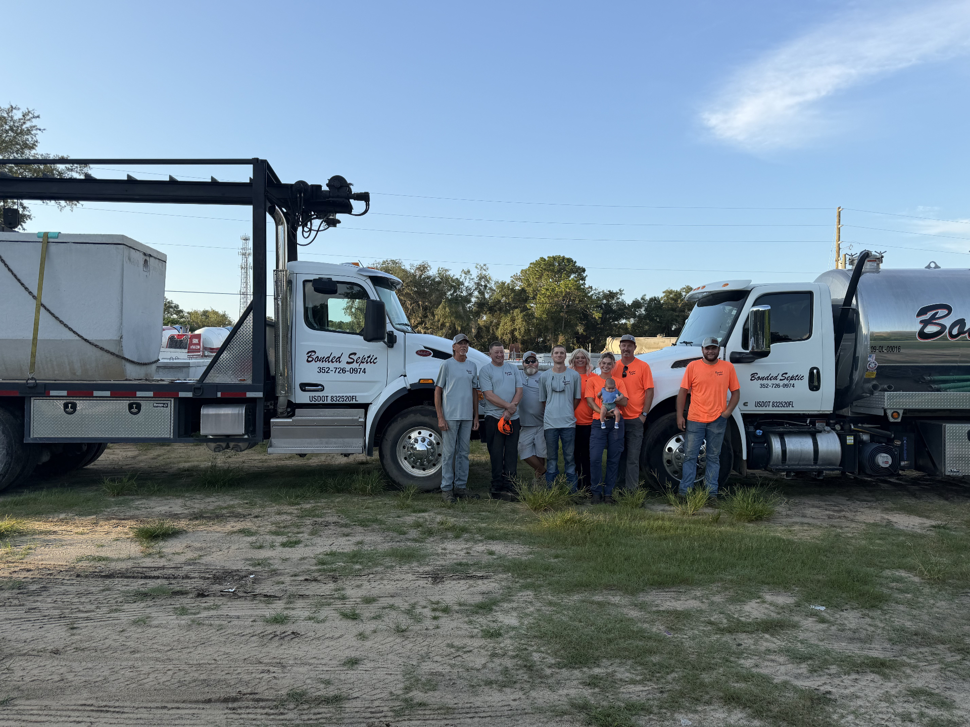 The Bonded Septic Tank family crew standing together in front of two company septic trucks in Hernando, Florida